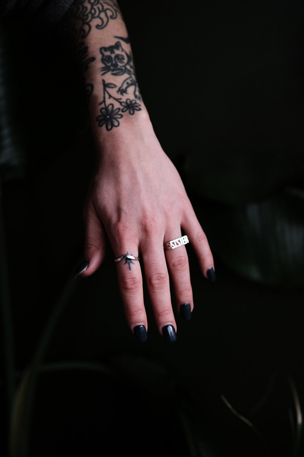 Hand with tattoos and rings on a dark background