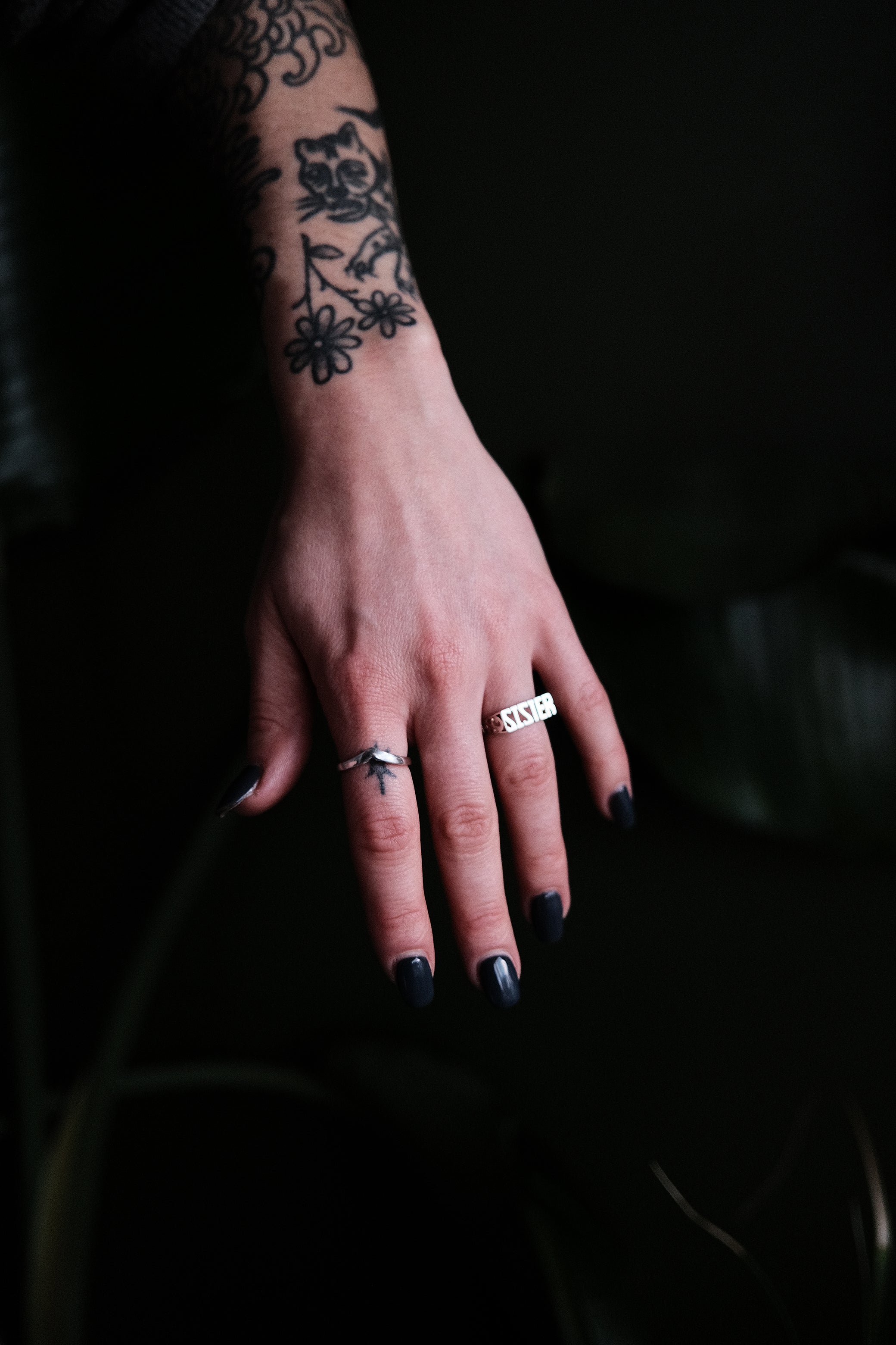 Hand with tattoos and rings on a dark background